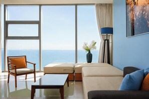 A modern living room with a view of the sea, a sofa, a chair, a coffee table, and a floor lamp. - Sea and Sun Apartments (Da Nang)