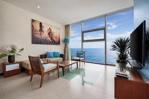 A modern living room with a large window, a flat-screen TV, and a painting on the wall. - Sea and Sun Apartments (Da Nang)