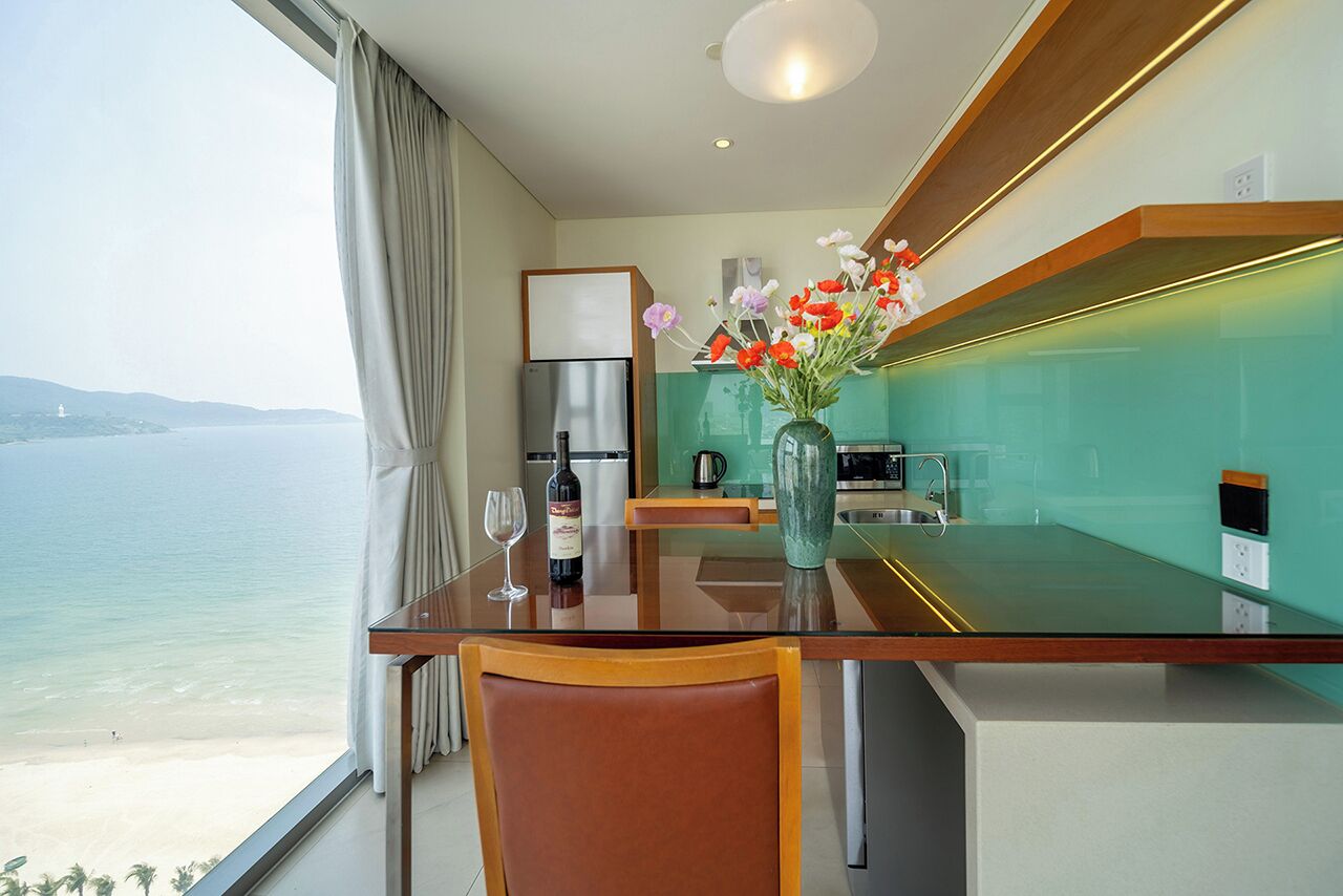 Eine moderne Küche mit Meerblick, einem Esstisch mit Stühlen und einer Vase mit Blumen.