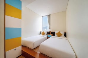 A hotel room with two beds, a window with curtains, a nightstand, and a view of the city. - Sea and Sun Apartments (Da Nang)