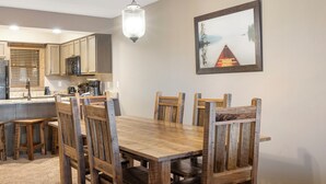 Un coin repas avec une table et des chaises en bois, un luminaire suspendu et un tableau encadré au mur.