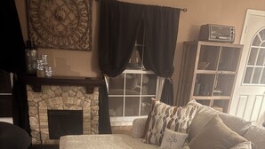 Una sala de estar acogedora con un sofá seccional, una mesa de centro de madera, una chimenea y un adorno de pared.