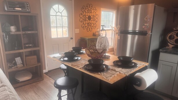 Una cocina con isla central, taburetes negros, refrigerador de acero inoxidable y un adorno de pared.