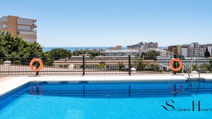 Une piscine équipée de bouées de sauvetage, une vue dégagée sur la mer et un paysage urbain en arrière-plan.