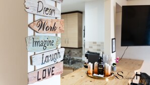 Une cuisine avec des panneaux en bois accrochés au mur, une machine à café et un téléviseur fixé au mur.