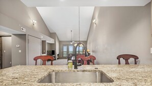 A kitchen with granite countertops, a stainless steel sink, and a ceiling fan. - Penthouse Condo + Suite, Gorgeous View of the Lake (Branson)
