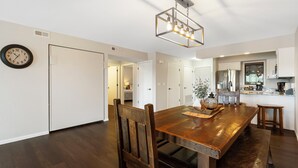 A spacious dining area with a wooden table and chairs, a modern chandelier, and a kitchen in the background. - Incredible 1 Bd Lake Condo with Resort Perks & Ticket Discounts! (Branson)