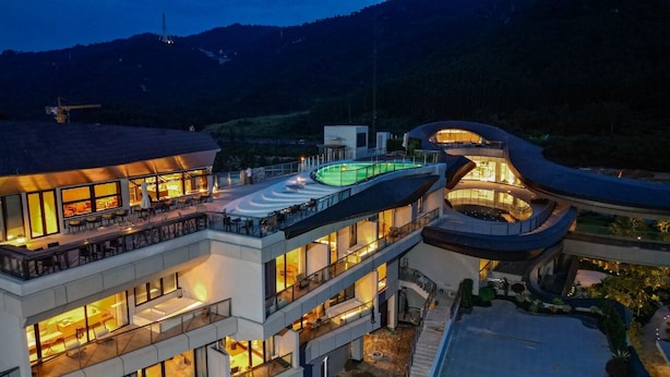 A modern hotel with multiple floors, outdoor seating areas, and a pool. - Semri Hotels&Resorts (Zhangzhou)