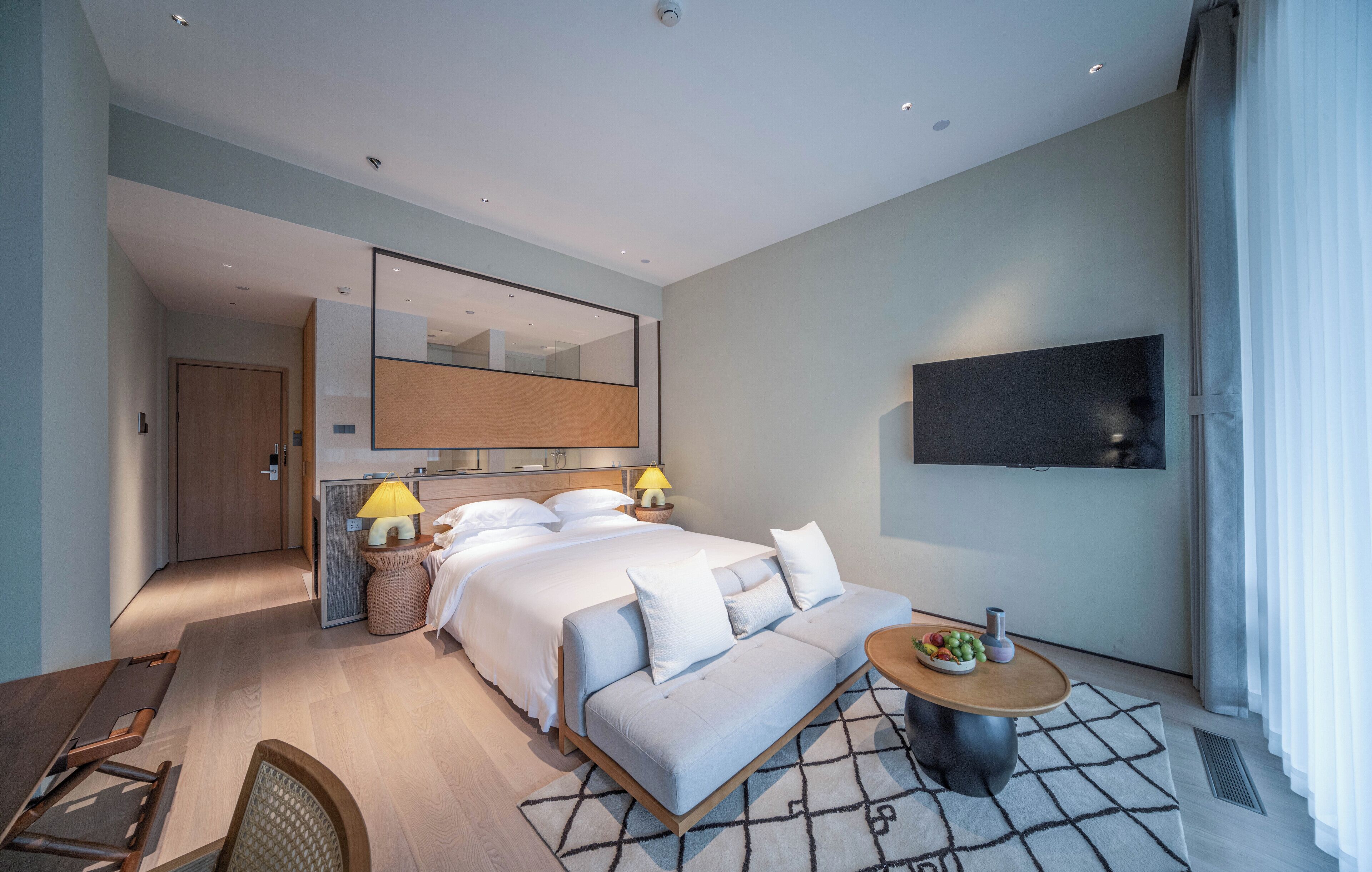 Une chambre d’hôtel moderne équipée d’un lit, de tables de chevet, d’un téléviseur et d’un coin repas.