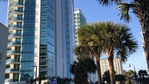 A tall hotel with a modern design, featuring a prominent 'Mr. & Mrs. Smith' sign, surrounded by palm trees and a clear blue sky. - Wake up to sweeping ocean views from the 16th floor at Oceans One (Myrtle Beach)