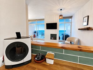 A modern living room with a large window, a flat-screen TV, and a ceiling fan. - Exclusive Sea View Apartment EHHouse (Buenas Noches)