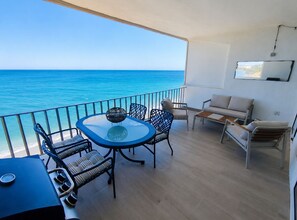 A balcony with a view of the sea, furnished with a table, chairs, and a sofa. - Exclusive Sea View Apartment EHHouse (Buenas Noches)