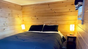 Una stanza con rivestimento in legno, un letto, due lampade da comodino e un tavolino con lampada.