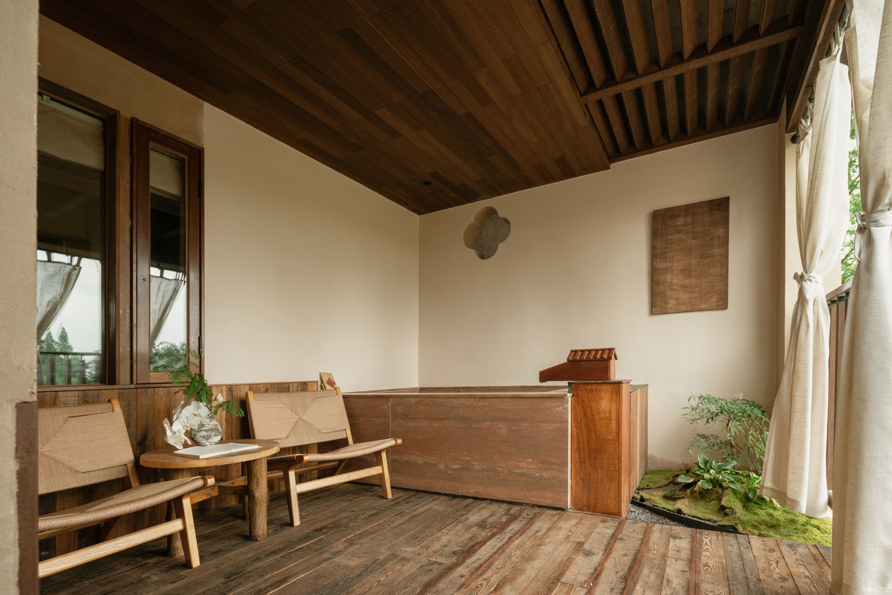 A wooden bench seating area with a wooden table, a reception desk, and a small plant.
