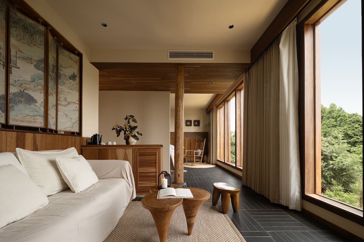 A modern living room with a sofa, coffee table, and a view of the outdoors through large windows.