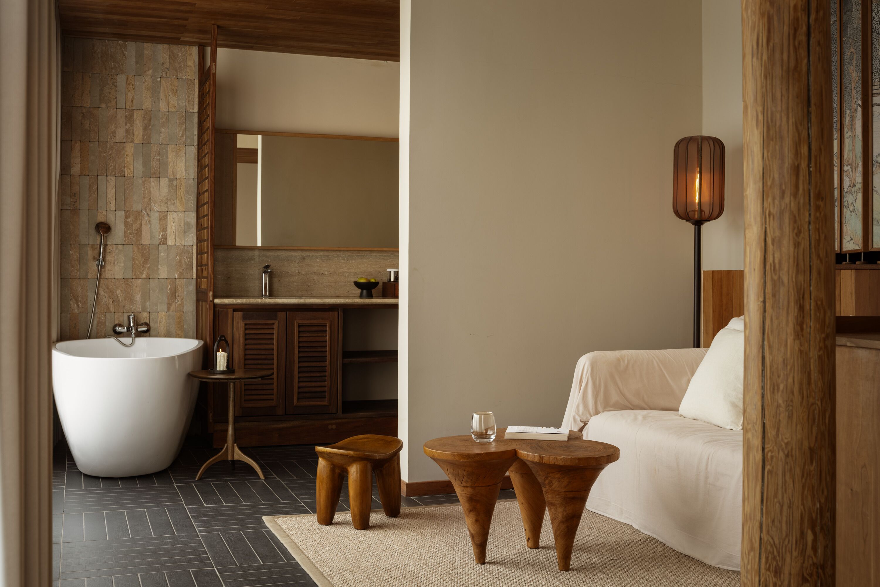 Un baño moderno con una bañera independiente, taburetes de madera y un espejo grande.