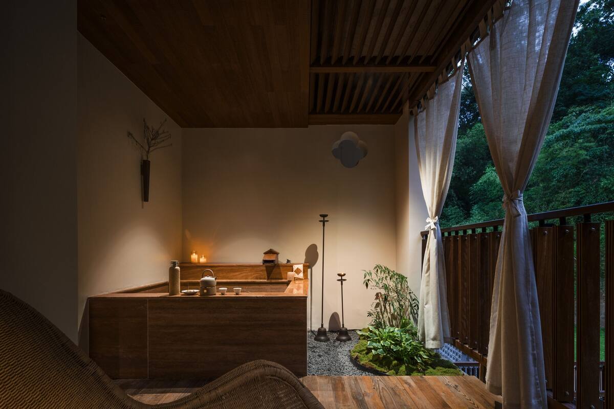 A serene spa area with a wooden reception desk, candles, and a small plant arrangement.