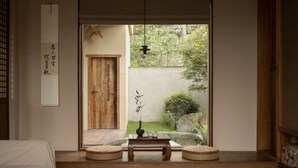 A traditional Japanese room with tatami flooring, a shoji screen door, a small wooden table with a vase and teapot, and a hanging light fixture. - Hegu Mountain Retreat (Chengdu)