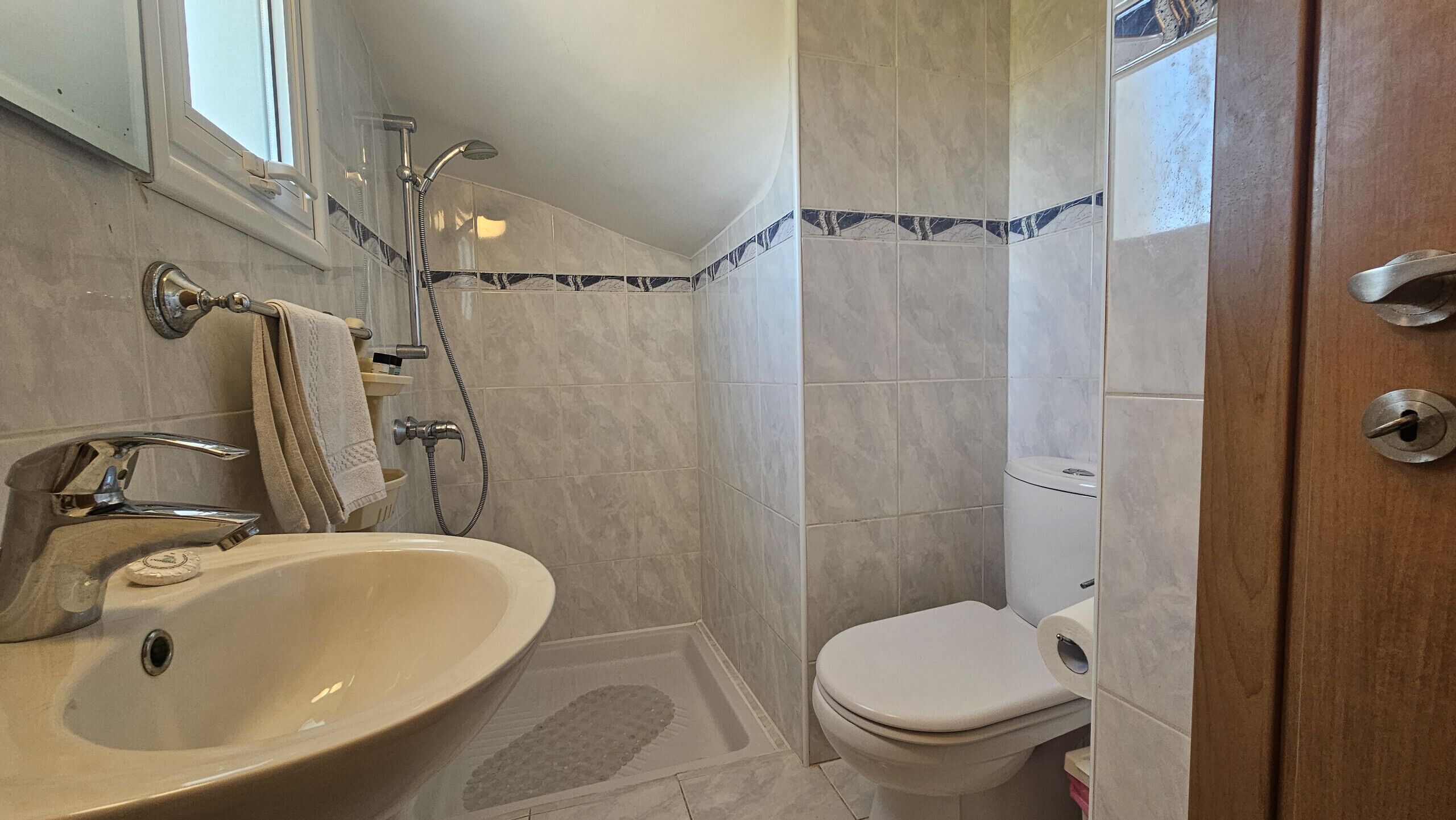 Un baño con lavamanos, inodoro, ducha y una puerta.