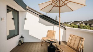 A balcony with two wicker chairs, a round table, and a white umbrella. - Shine on (Suzhou)