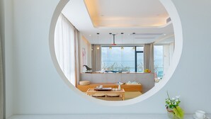 A modern room with a circular window, a wooden table with a tray, a small vase with flowers, and a cup on a saucer. - Tianya Jingxi Seaview Inn in Sanya (Sanya)