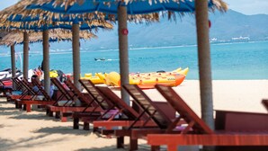 A beach with thatched umbrellas and wooden lounge chairs. - Tianya Jingxi Seaview Inn in Sanya (Sanya)