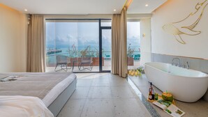 A modern hotel room with a large bed, a bathtub, and a balcony with a view of the sea. - Tianya Jingxi Seaview Inn in Sanya (Sanya)