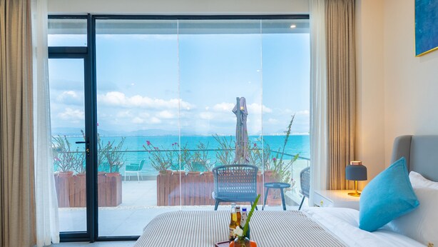 A hotel room with a large sliding glass door leading to a balcony with a view of the sea. - Tianya Jingxi Seaview Inn in Sanya (Sanya)
