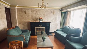 Un salon avec deux canapés, une table basse, une cheminée et un lustre.
