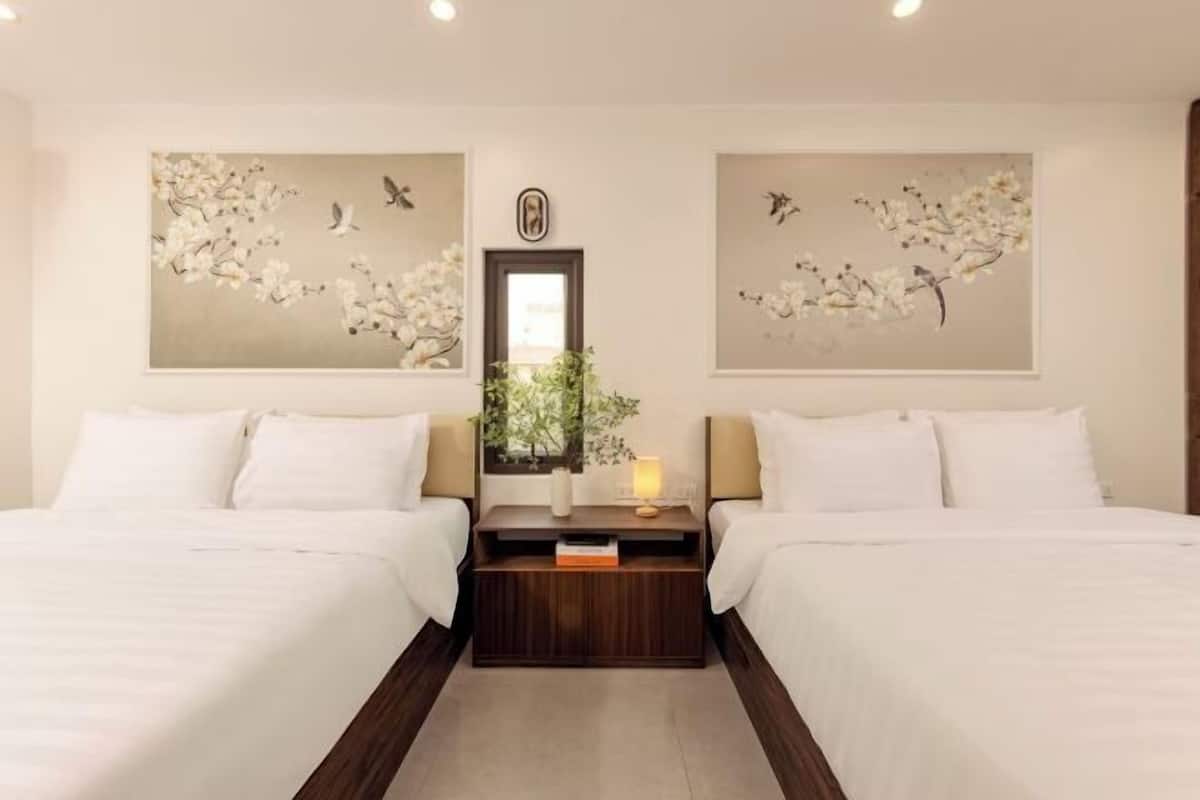 Habitación de hotel con dos camas, una mesita de noche con lámpara, un espejo y decoración en la pared.