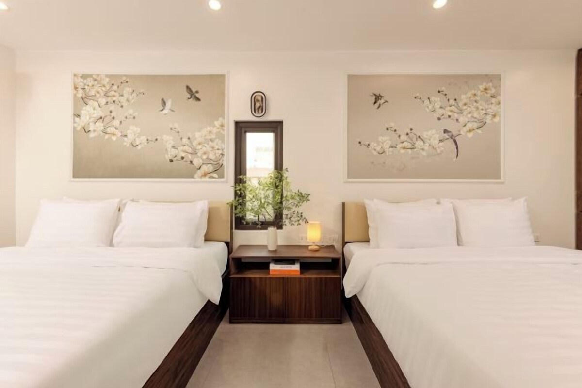 Une chambre d’hôtel avec deux lits, une table de chevet avec une lampe, un miroir et des œuvres d’art murales.