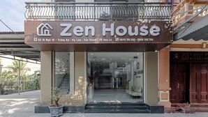 Un bâtiment sur lequel est apposée une enseigne indiquant « Zen House » et qui affiche les coordonnées.