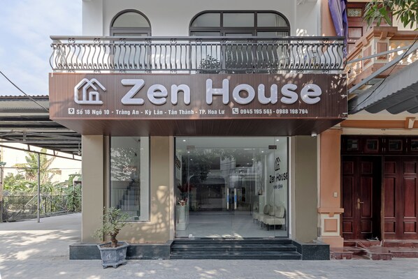 A building with a sign reading "Zen House" and contact information.