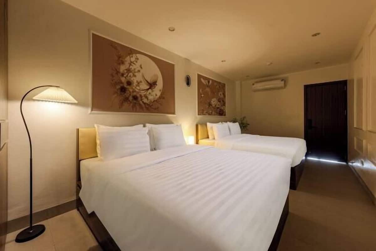 Habitación de hotel con dos camas, una lámpara de pie y decoración en las paredes.