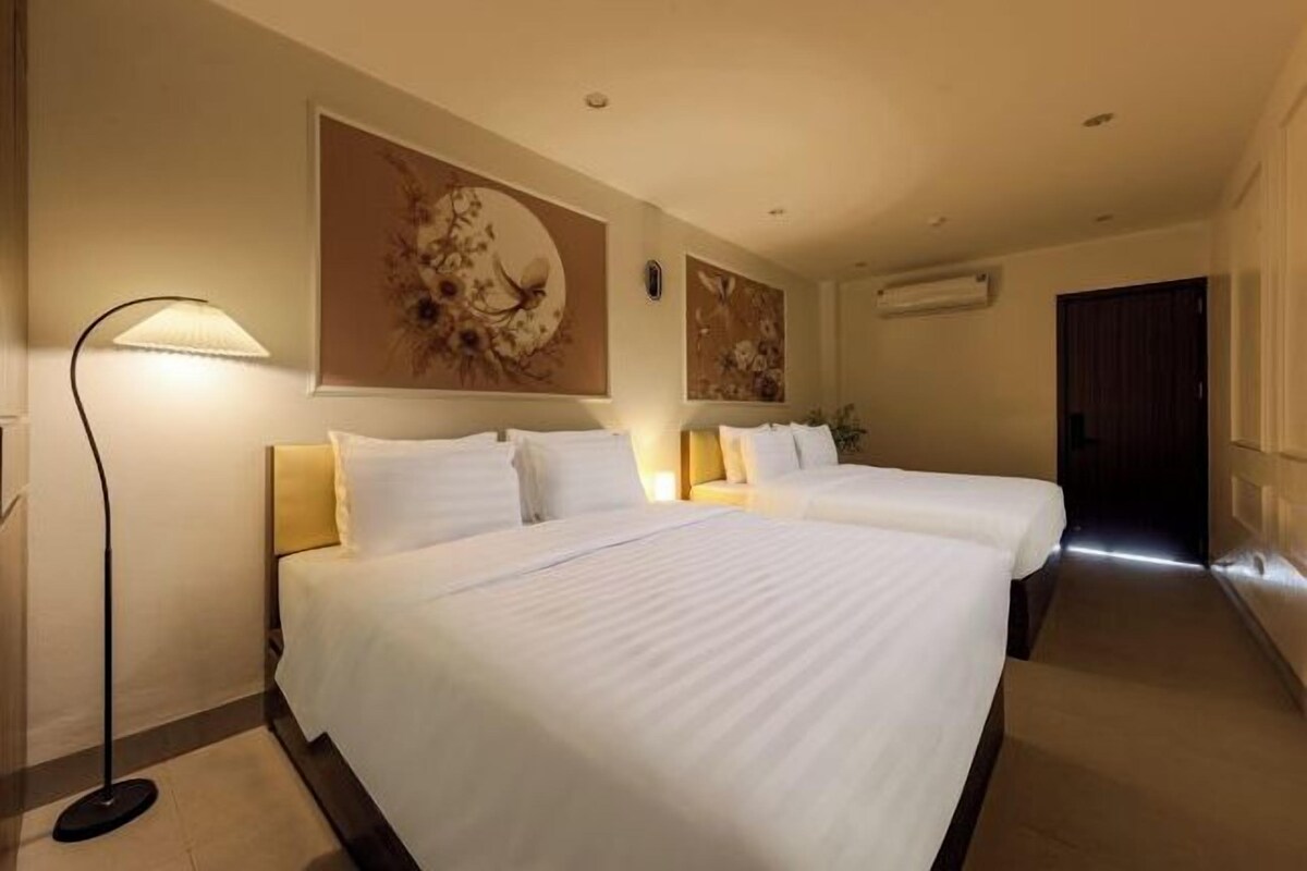 Une chambre d’hôtel avec deux lits, une lampe sur pied et des œuvres d’art murales.