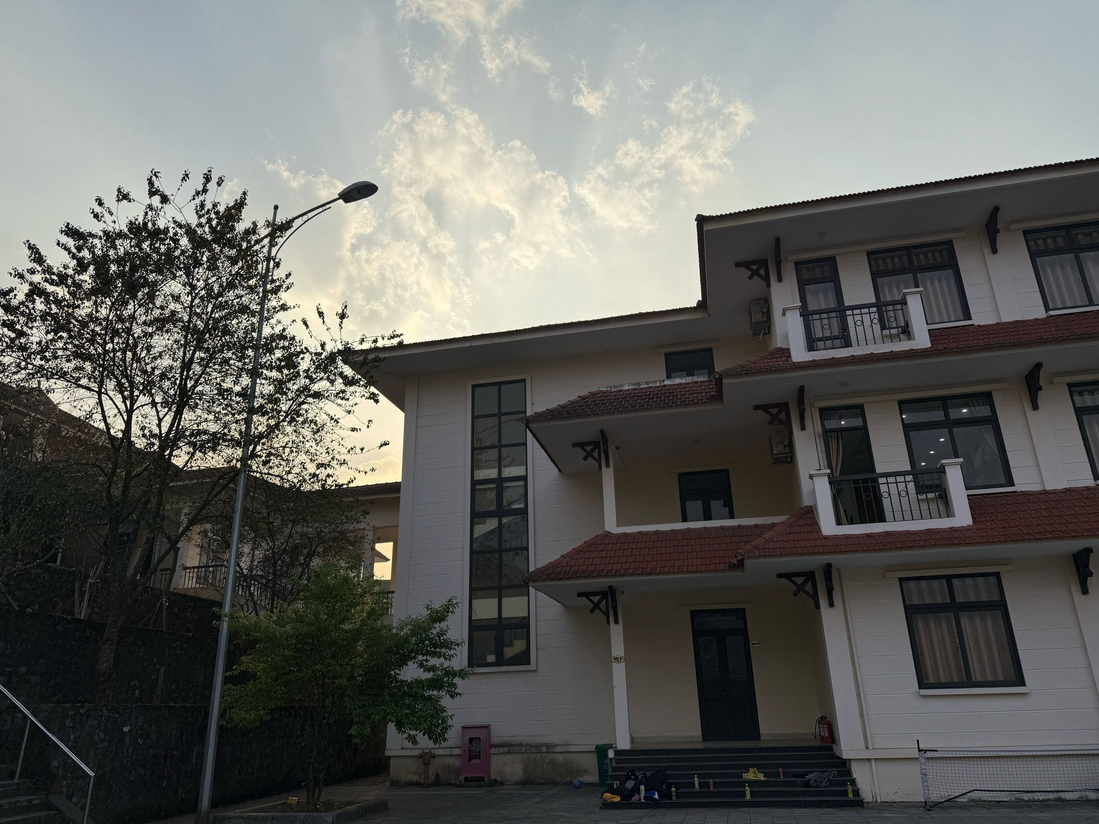A multi-story building with a flat roof, large windows, and a balcony on the upper floor.