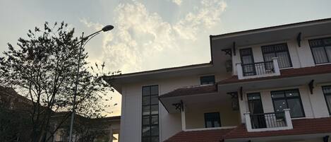 A multi-story building with a flat roof, large windows, and a balcony on the upper floor.