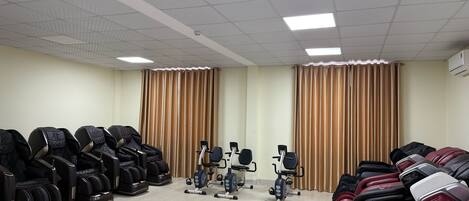 A room with massage chairs, exercise bikes, and a ceiling with recessed lighting.