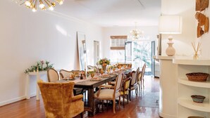 Comedor con una larga mesa de madera dispuesta para una comida, rodeado de sillas tapizadas.