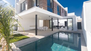 A modern two-story house with a swimming pool, outdoor seating, and a well-maintained lawn.