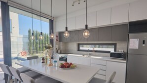 Una cocina moderna con una isla central, electrodomésticos de acero inoxidable e iluminación colgante.