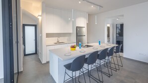 Una cocina moderna con armarios blancos, una isla central con taburetes y un refrigerador integrado.