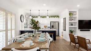 A modern kitchen with white cabinets, a central island, and pendant lighting.