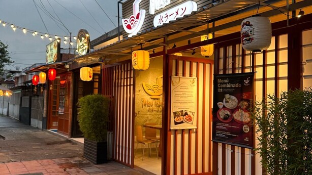 A restaurant with a signboard, outdoor seating, and a menu board. - BAMUKA HOSTEL (Bogotá)