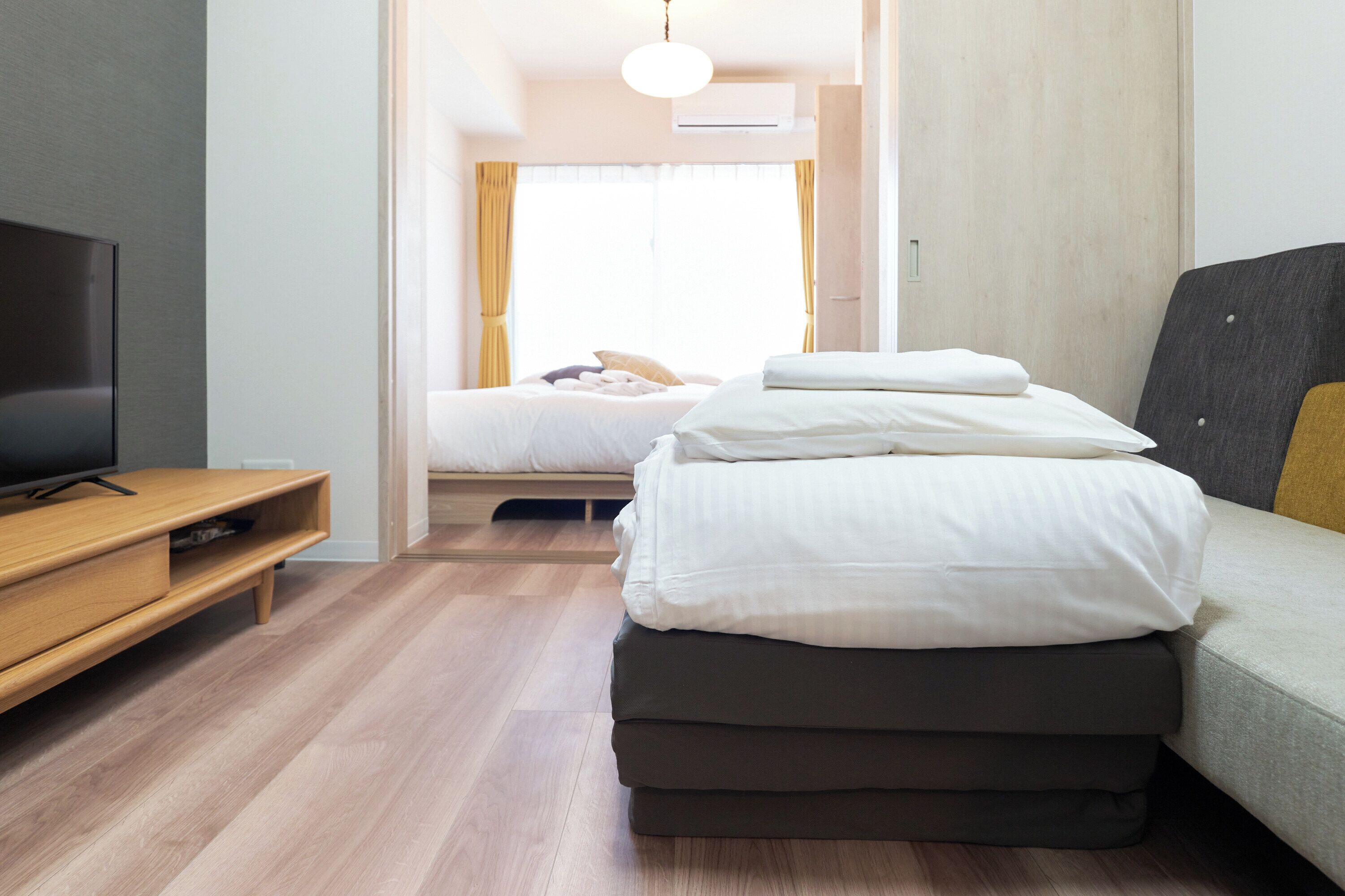 A hotel room with a bed, a TV, and a wooden floor.