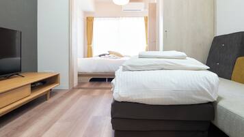 A hotel room with a bed, a TV, and a wooden floor.