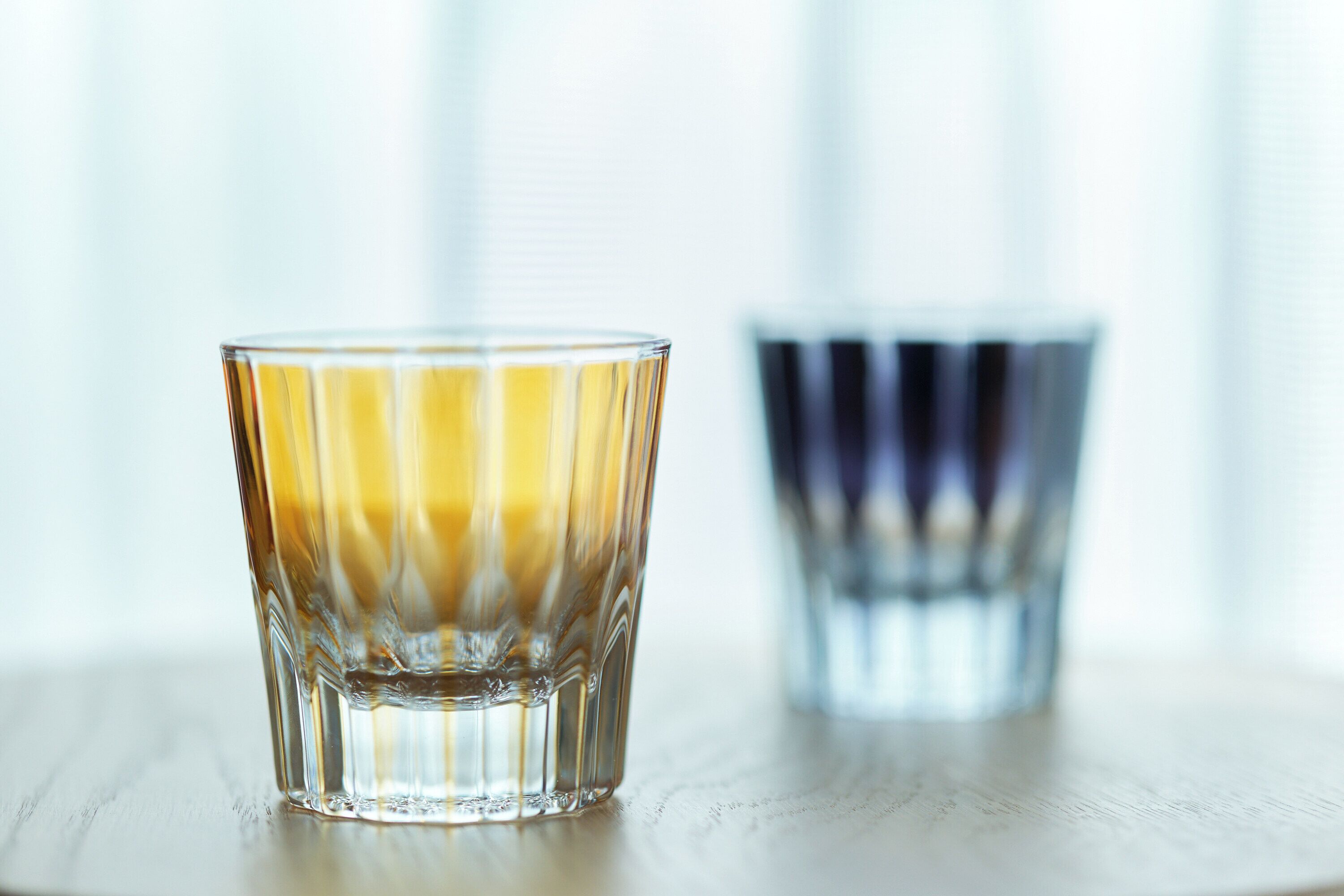 A glass of amber liquid on a wooden surface with a blurred background.