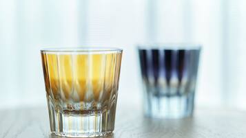 A glass of amber liquid on a wooden surface with a blurred background.