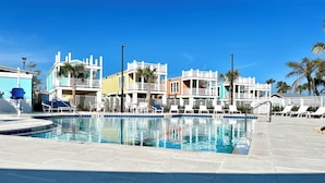 A swimming pool with lounge chairs and a building with colorful facades. - New Waterfront❗️Pool, Epic Views/Corner Lot❤️Beaches near~BBQ Grill~Washer/Dryer (Jensen Beach)