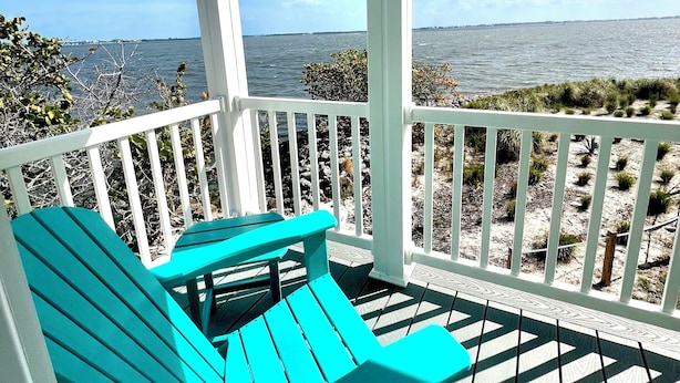 A covered porch with two turquoise Adirondack chairs, white railings, and a view of the ocean. - New Waterfront❗️Pool, Epic Views/Corner Lot❤️Beaches near~BBQ Grill~Washer/Dryer (Jensen Beach)